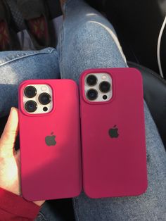 two pink iphones sitting next to each other on a person's lap top