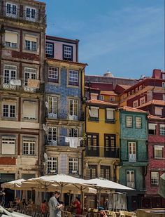 people sitting at tables in front of colorful buildings