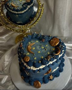 there is a blue cake with stars and moon decorations on the top, next to a mirror