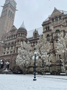 an old building with snow on the ground and trees in front of it covered in snow