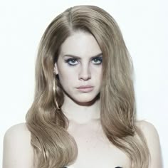 a woman with long blonde hair and blue eyes wearing a strapless bra, posing for the camera