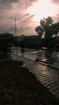 the sun shines brightly through the clouds in the distance as people ride their bikes down the street