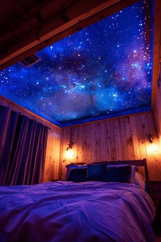 a bedroom with a bed and a sky filled with stars on the ceiling above it