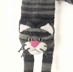 a knitted cat hat and scarf hanging on a wall