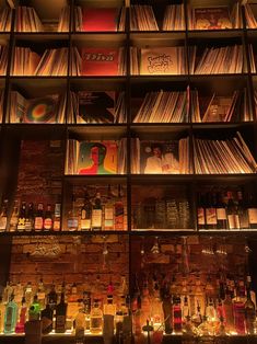 the shelves are full of liquor bottles and cd's in front of them, all lit up by candles