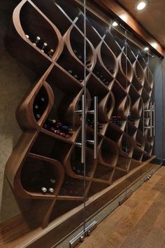 a wine rack in the corner of a room next to a glass wall with bottles on it