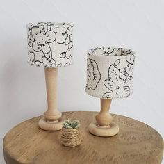 two small lamps on a wooden table next to each other