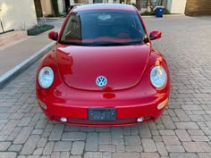 the front end of a red car parked on a brick road