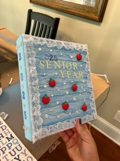 someone is holding up a book that has strawberries on it and the words senior year written in gold