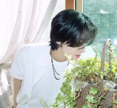 a young man sitting next to a basket filled with plants