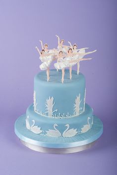 a blue cake topped with ballet figurines on top of it