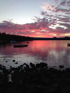 the sun is setting over a lake with boats in it