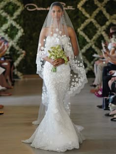 the bride is walking down the runway in her wedding dress and veil with flowers on it