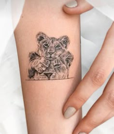 a woman's arm with a small tattoo of two lions on the left side