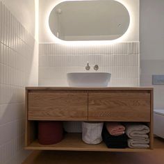 a bathroom with a sink, mirror and towels on the shelf in front of it