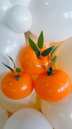 three orange tomatoes sitting on top of white balloons