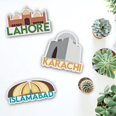 three stickers depicting the name of different countries on a white surface next to succulents and cacti