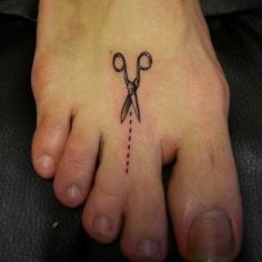 a small tattoo on the foot of a person with scissors