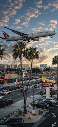 an airplane is flying over a mcdonald's sign and palm trees in the foreground