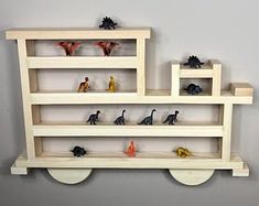 a wooden shelf with toy dinosaurs on it