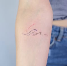 a woman's arm with a small wave tattoo on the left side of her arm