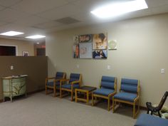 a waiting room with blue chairs and pictures on the wall