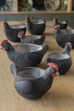 six ceramic chickens sitting on top of a wooden table