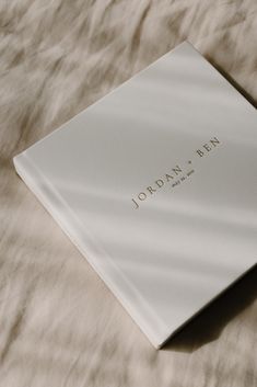 an open book sitting on top of a bed covered in white sheets and furnishing