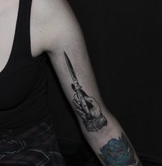 a woman with a tattoo on her arm holding a knife in one hand and a rose in the other