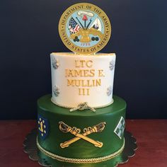 a three tiered cake with an emblem and name on the top, sitting on a table