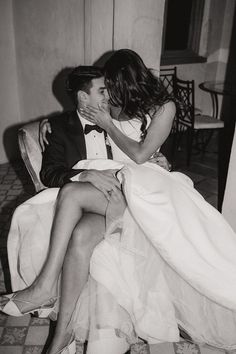 a man and woman sitting next to each other on a chair in black and white