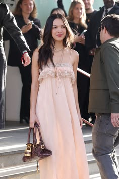 a woman in a pink dress holding a brown purse