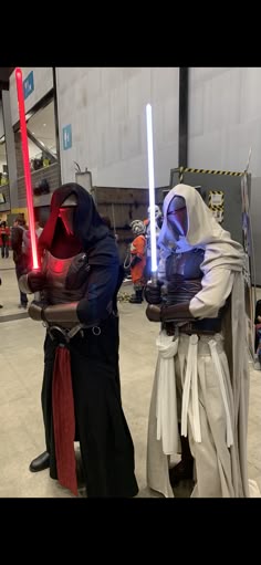 two people dressed in costumes holding lightsabes