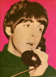 a young man talking on a telephone while wearing a green shirt