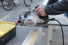 a man using a circular saw to cut wood with an electric grinder on a workbench
