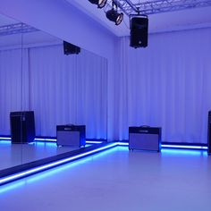 an empty room with blue lighting and speakers