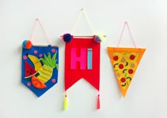 three handmade wall hangings with fruit and vegetables on them, one has a slice of pizza