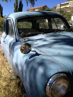 an old blue car is parked in the grass