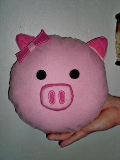 a hand holding a pink pig stuffed animal