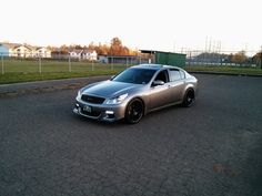 a silver car parked on the side of a road next to a fence and grass field