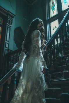 a woman in a white dress is walking down the stairs