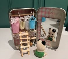 there is a small doll in a tin with clothes on it and a dog figurine next to it