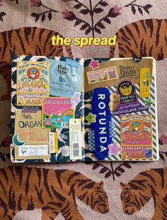 an open book with many different things on it sitting on a tiger print cloth covered tablecloth
