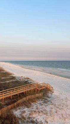 an empty beach next to the ocean at sunset