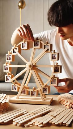 a man is making a ferris wheel out of popsicle sticks and wooden dows