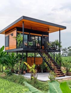 a small house that is in the middle of some grass and trees with stairs leading up to it