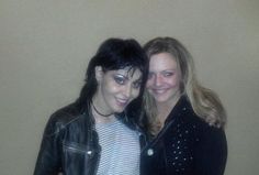 two women standing next to each other in front of a wall