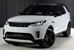 a white land rover is parked in front of a curtained room with black trim