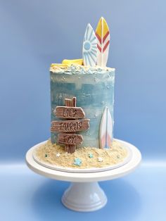 there is a cake that has been decorated with surfboards and sand on the beach