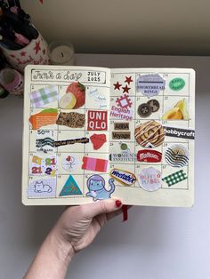 a hand holding an open planner with stickers on it